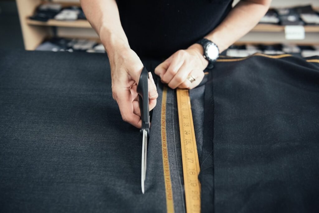 A tailor cutting luxury cloth for a suit. Cloth by Pepper Lee. Please credit https://pepperlee.co.uk/ when using this image.