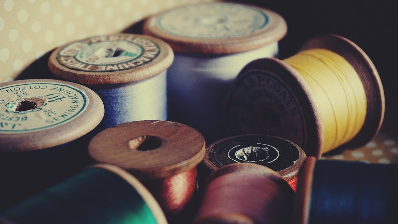 A close-up of vintage wooden spools displaying colorful sewing threads for crafting and tailoring.