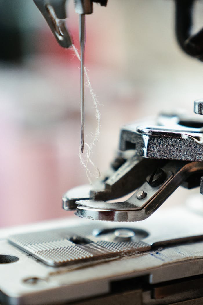 Detailed view of a sewing machine needle with thread, poised for stitching.