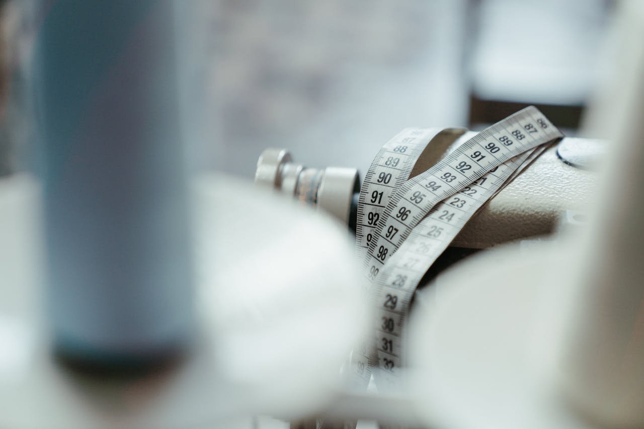 A sewing machine with a measuring tape draped over, emphasizing tailoring and craftsmanship.